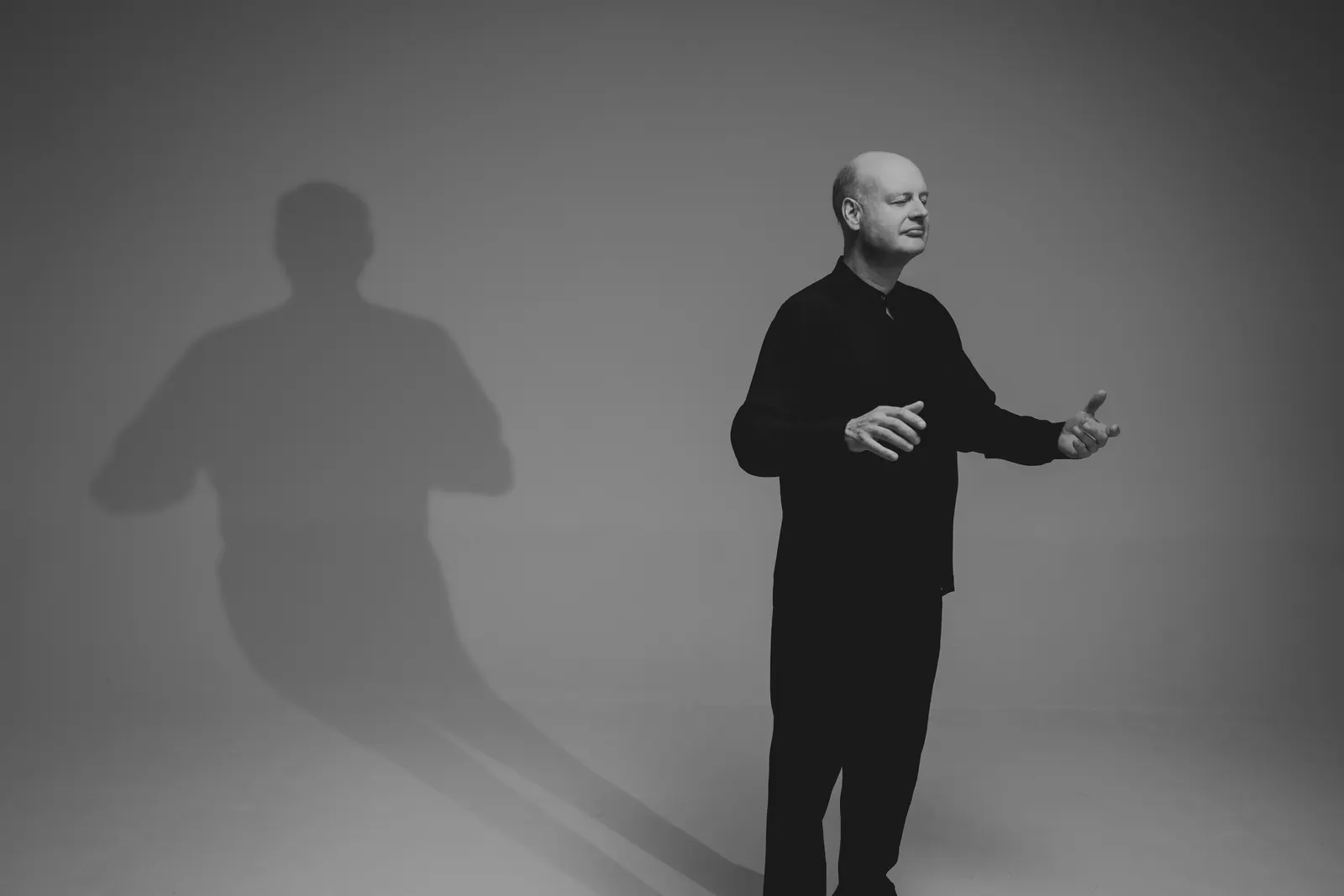 Stephen Layton conducting, his shadow on the wall behind him